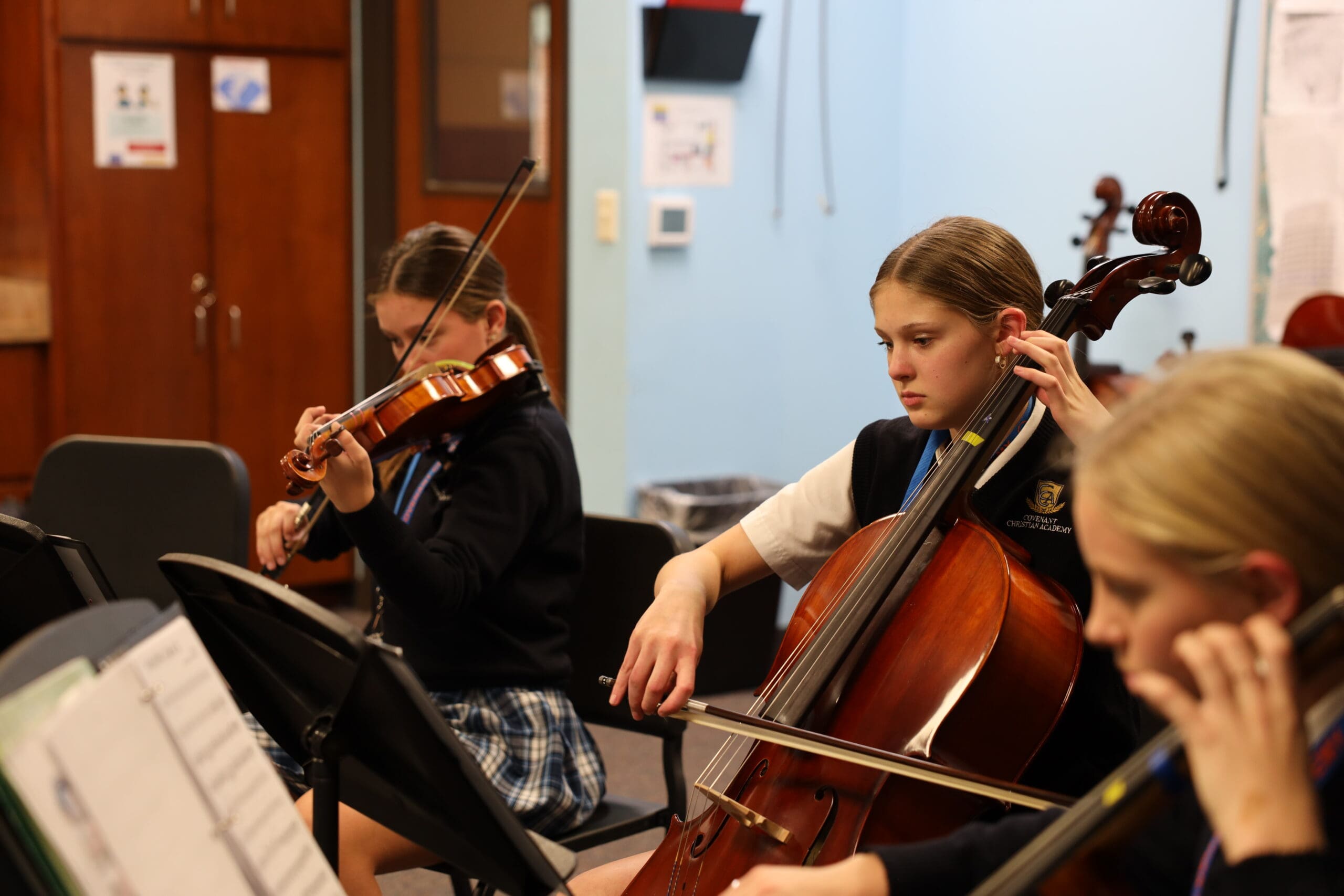 three middle school girls playing instruments in class during a lesson